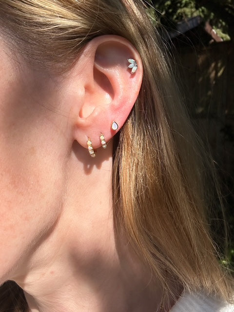 Sterling silver teardrop shape opal stud earrings with opal huggie hoop earrings in model's ear