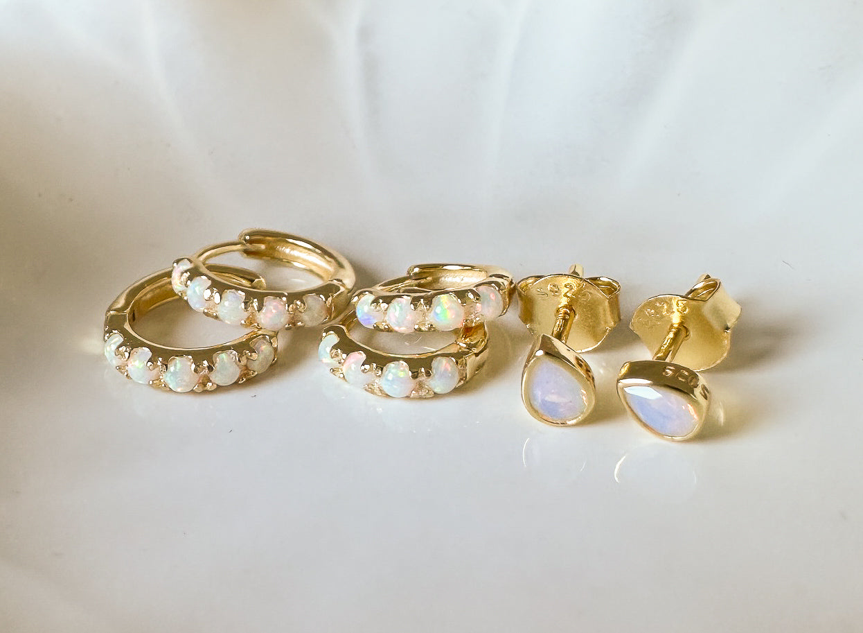 Set of gold hoop earrings with opal stones on a white background