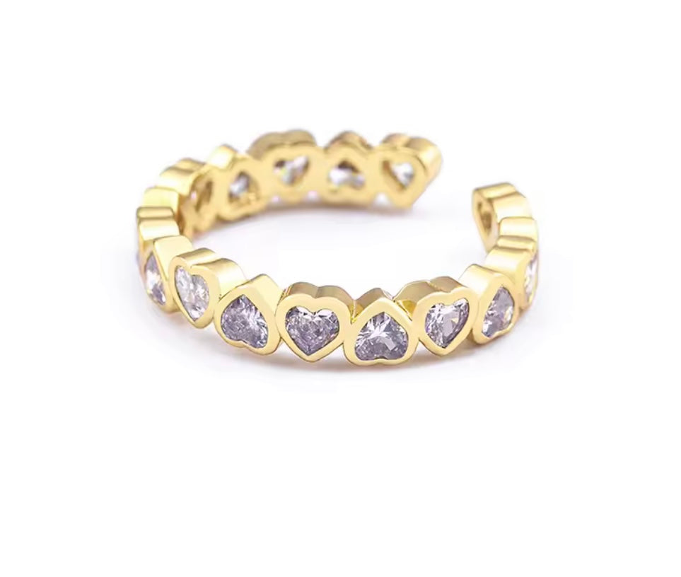 
                  
                    Gold ring with heart-shaped gemstones on a white background
                  
                