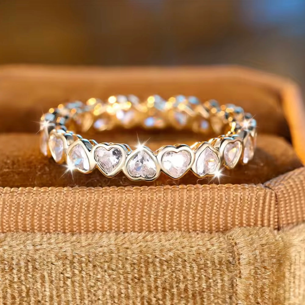 Gold bracelet with heart-shaped gemstones on a textured surface