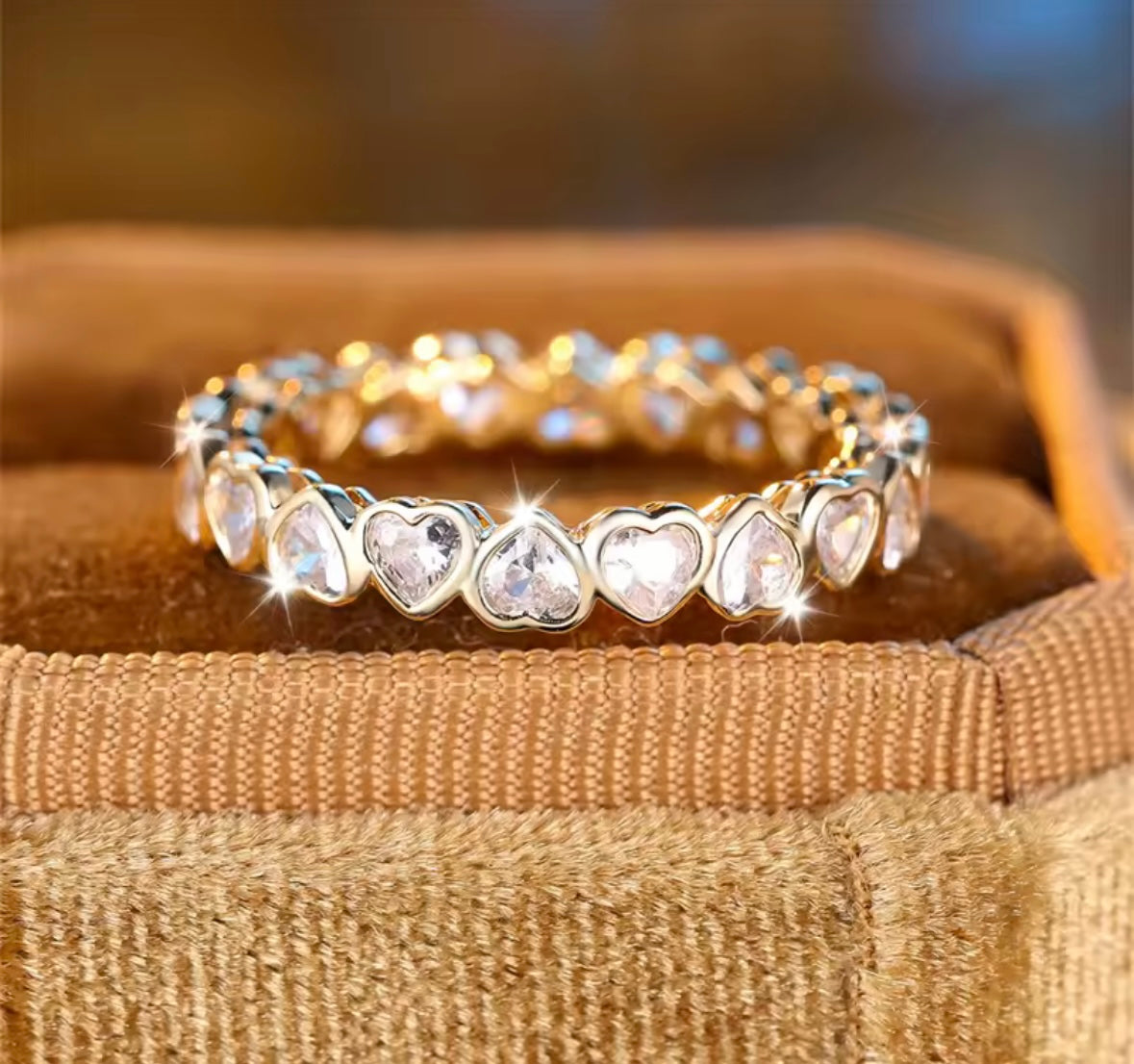 Gold bracelet with heart-shaped gemstones on a textured surface