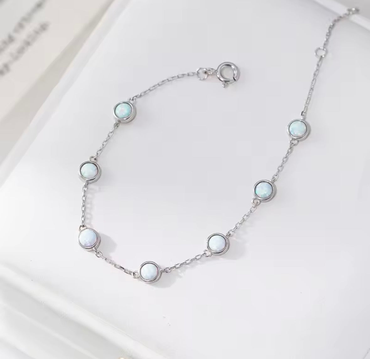 Silver bracelet with opal gemstones on a white surface