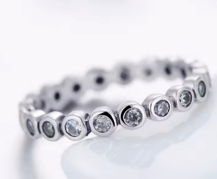 
                  
                    Sterling Silver ring with small CZ bezel set stones on a light background
                  
                