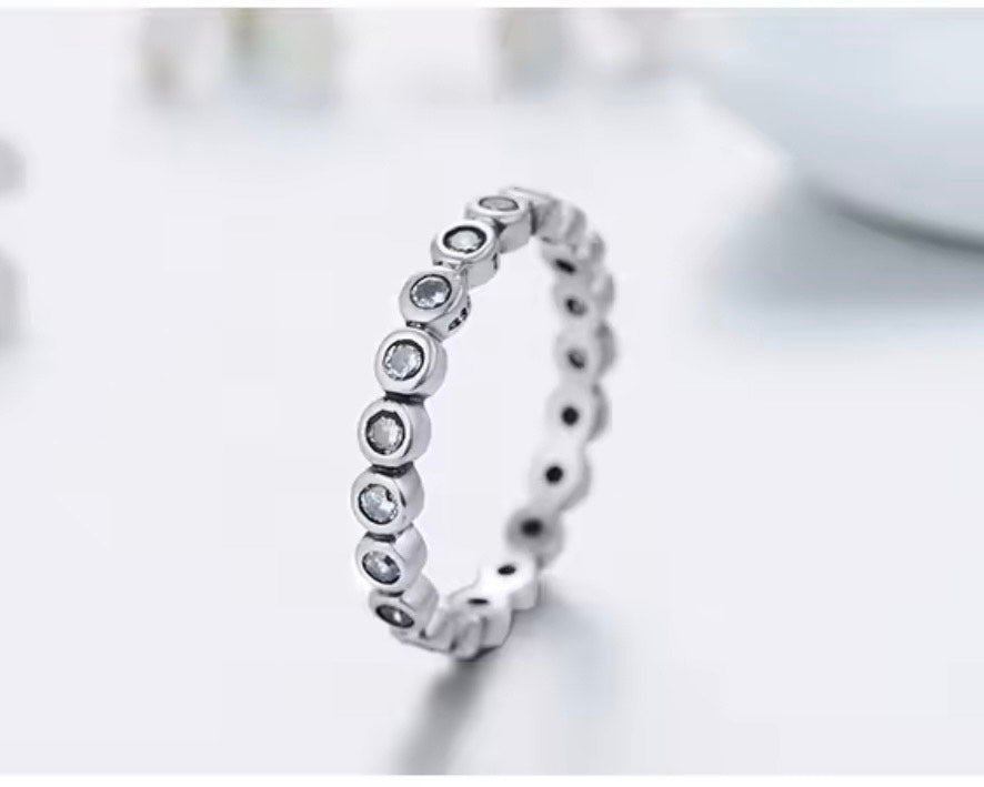 
                  
                    Sterling Silver ring with small CZ bezel set stones on a light background
                  
                