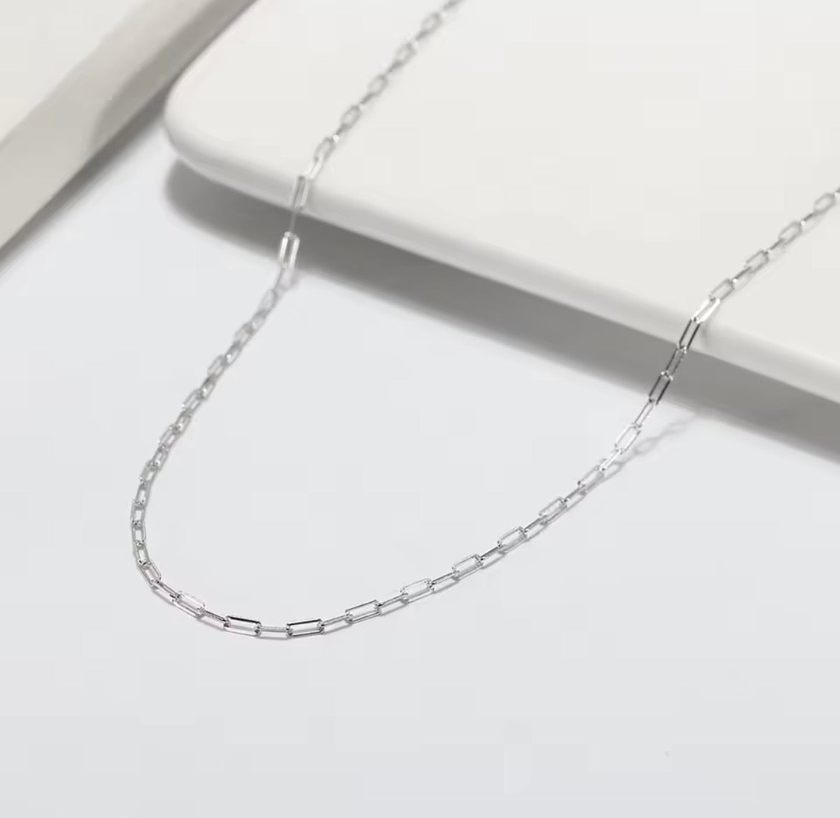 Silver chain necklace on a light gray background