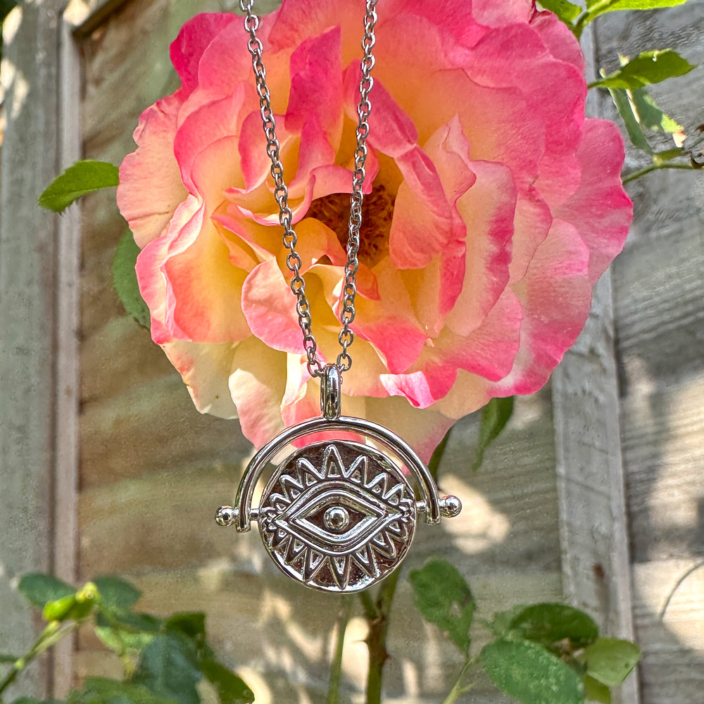 
                  
                    Necklace with a decorative pendant in front of a pink rose
                  
                