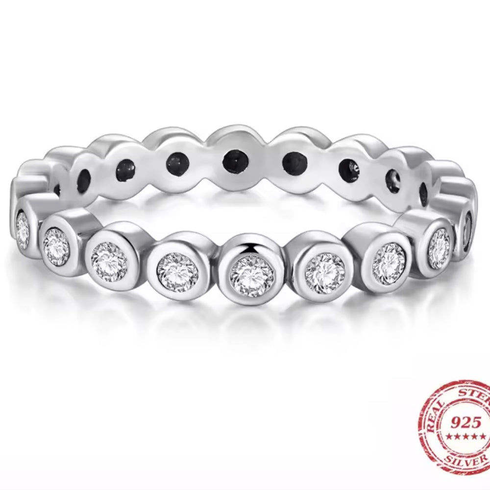 Silver ring with embedded bezel set CZ stones on a white background, featuring a 'Real Sterling 925' stamp.