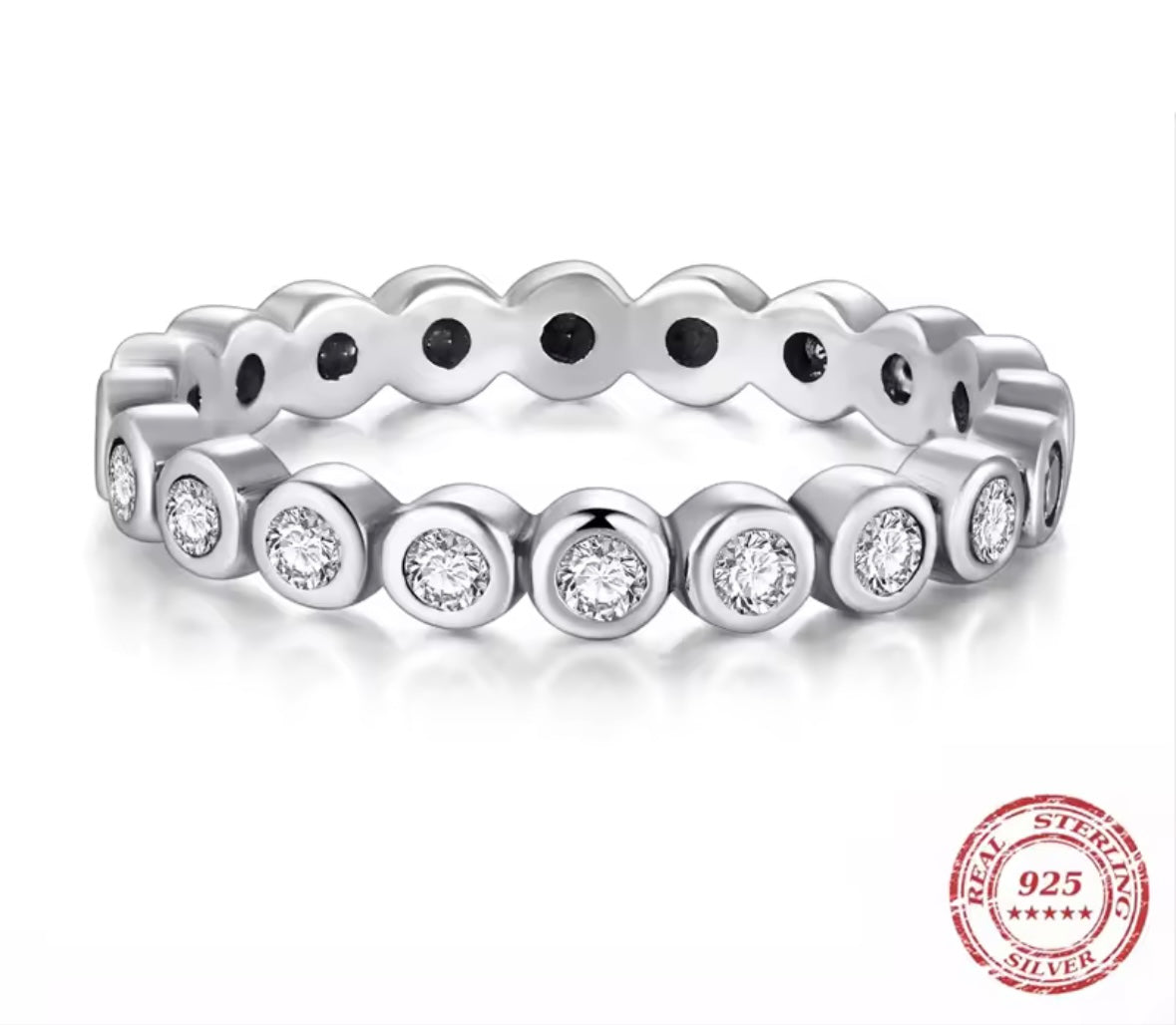 Silver ring with embedded bezel set CZ stones on a white background, featuring a 'Real Sterling 925' stamp.