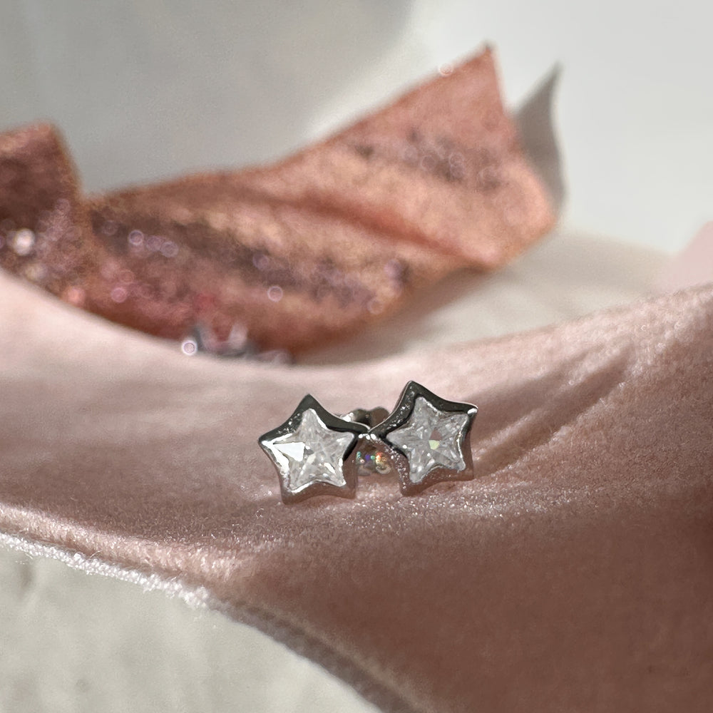 cubic zirconia star shaped silver earrings on pink ribbon