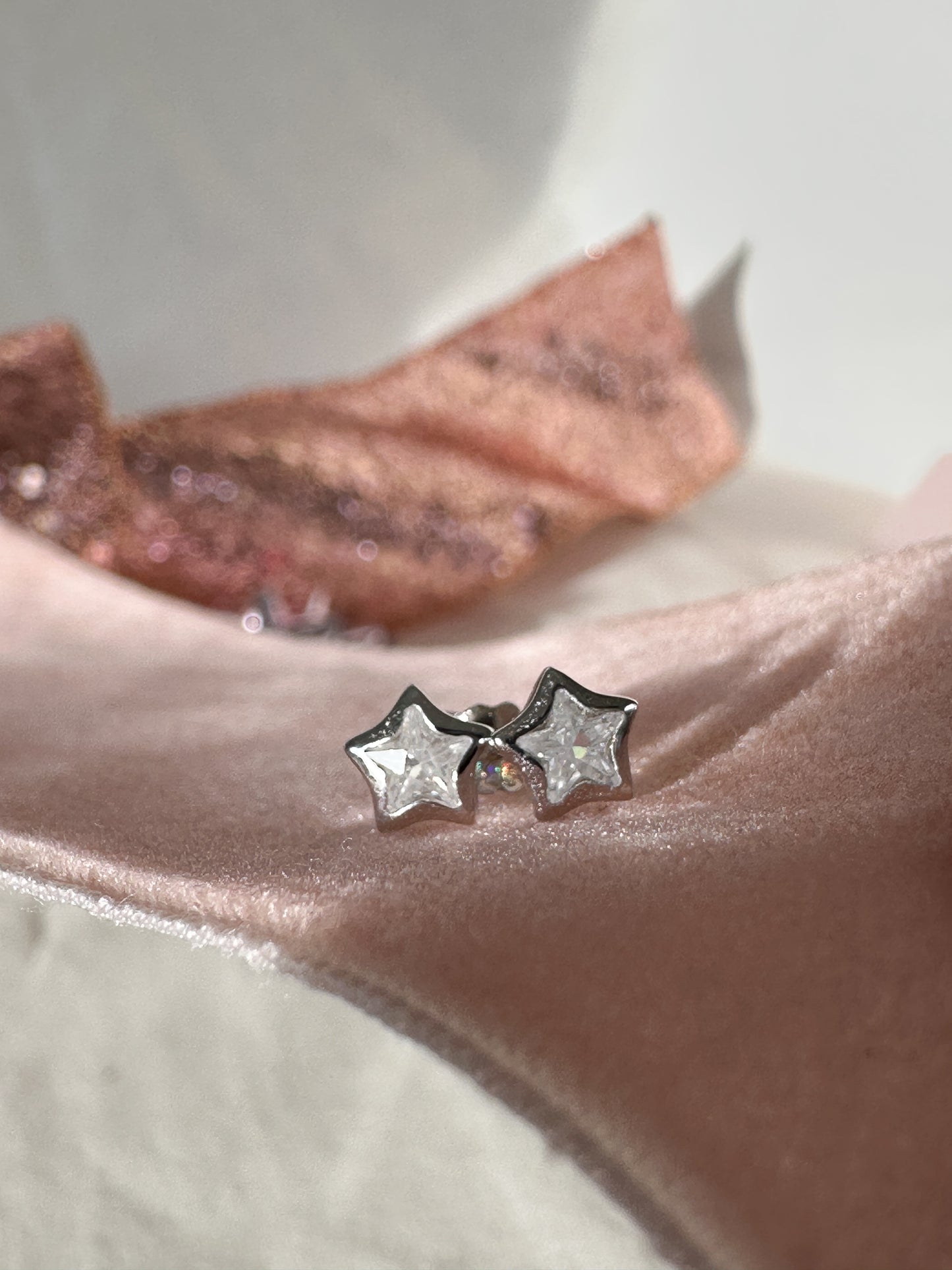 cubic zirconia star shaped silver earrings on pink ribbon